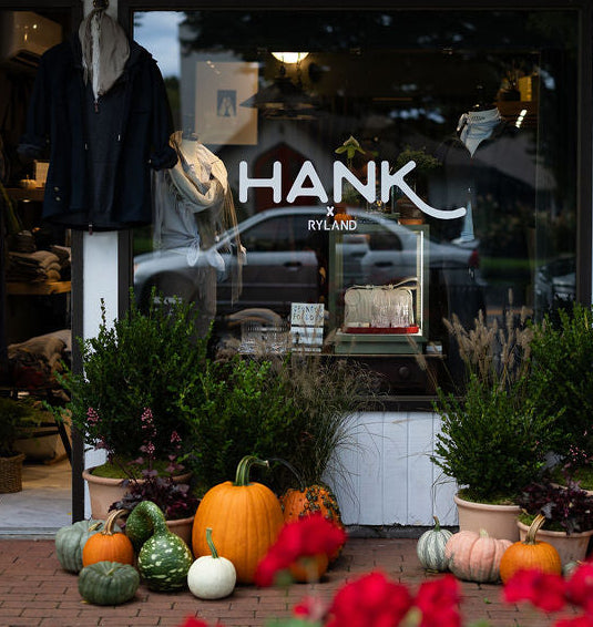 Storefront with 'Hank' branding, outdoor decorations, and a sign for 'Hamptons Boat & Yacht Concierge'.