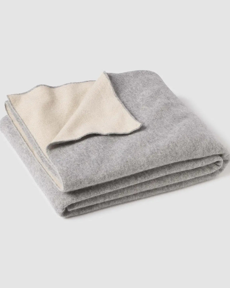 Folded gray blanket with cream-colored interior on a light gray background